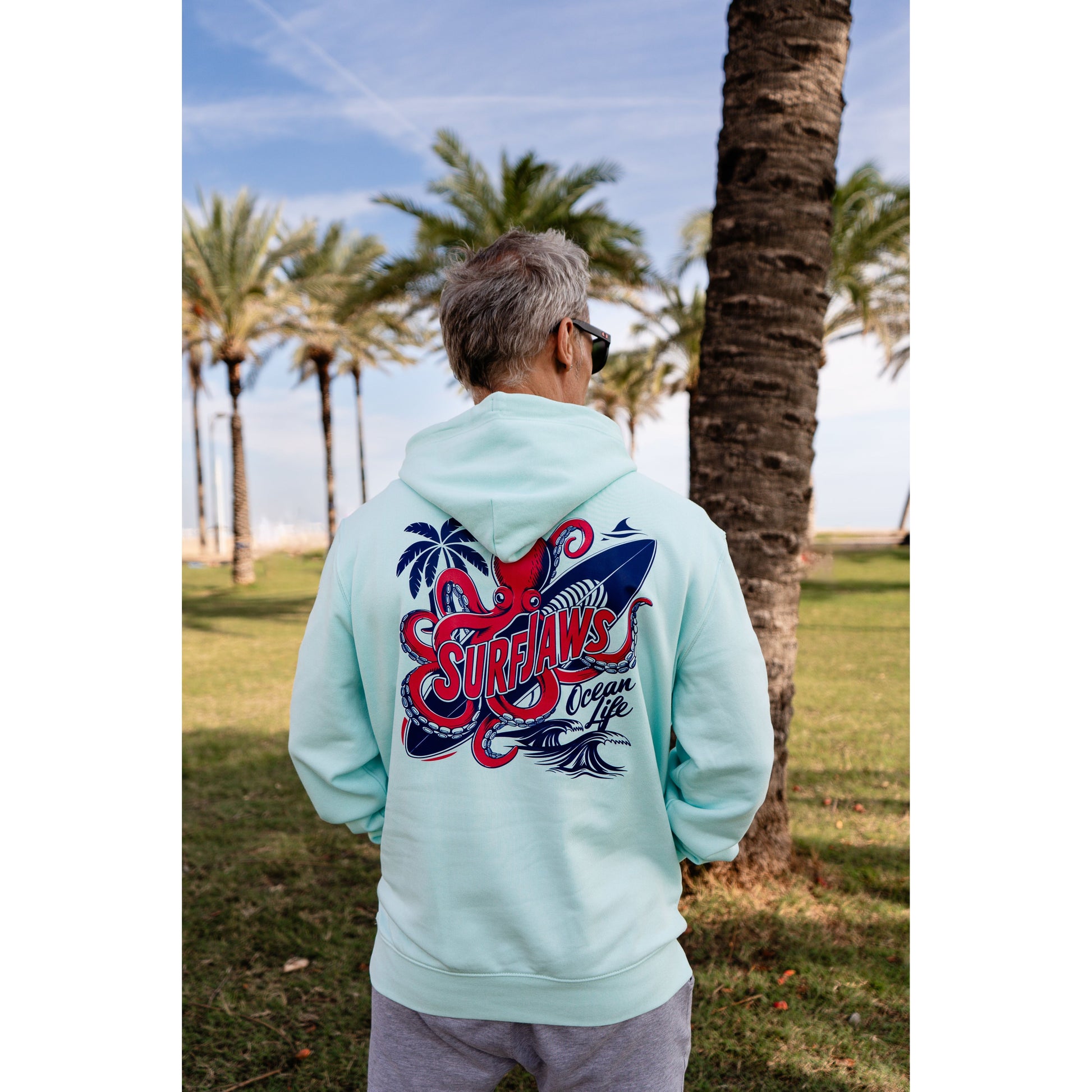 Sudadera SurfJaws de algodón orgánico en tono Ice Mint, ajuste regular. El modelo lleva una talla L, mide 1,62 m y tiene complexión atlética, mostrando un estilo cómodo y ecológico