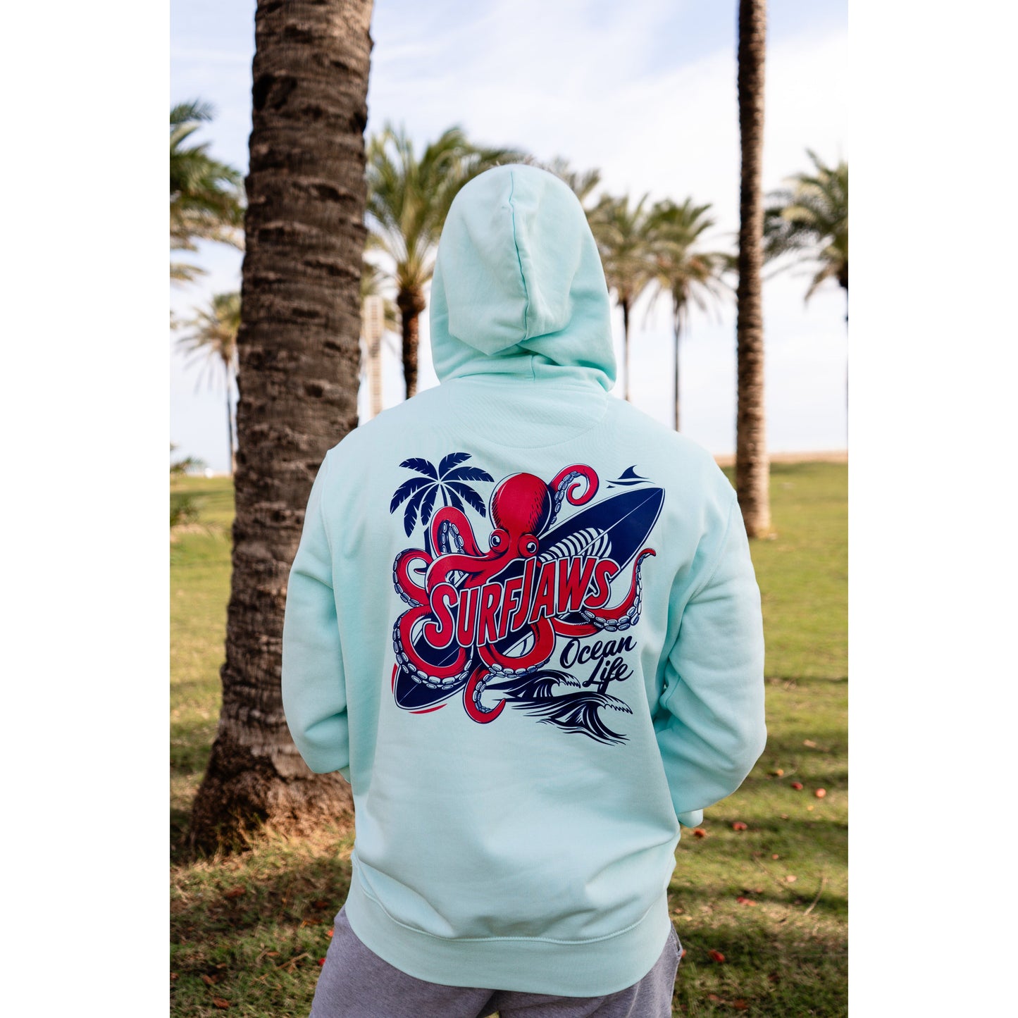 Sudadera SurfJaws de algodón orgánico en tono Ice Mint, ajuste regular. El modelo lleva una talla L, mide 1,62 m y tiene complexión atlética, mostrando un estilo cómodo y ecológico