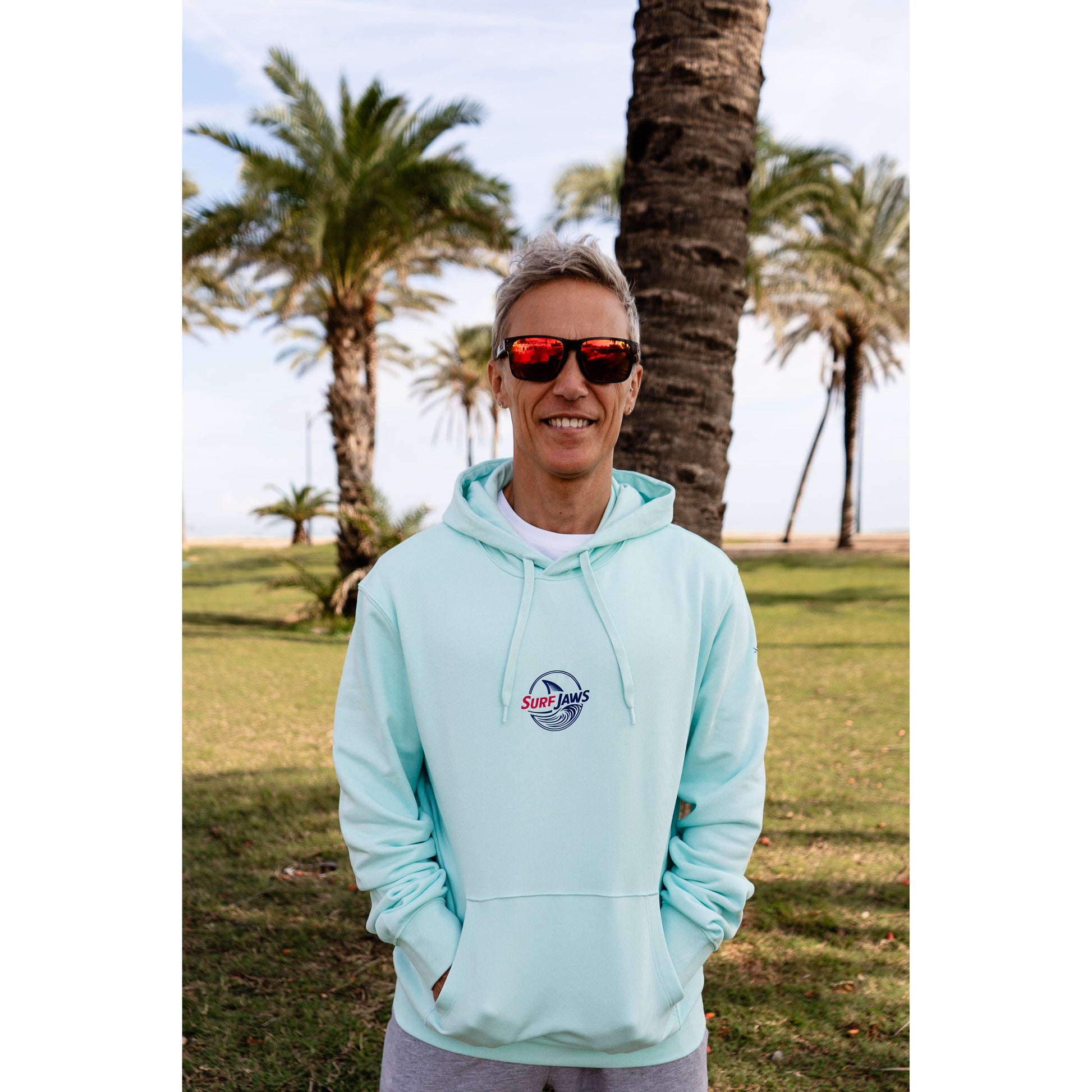 Sudadera SurfJaws de algodón orgánico en tono Ice Mint, ajuste regular. El modelo lleva una talla L, mide 1,62 m y tiene complexión atlética, mostrando un estilo cómodo y ecológico