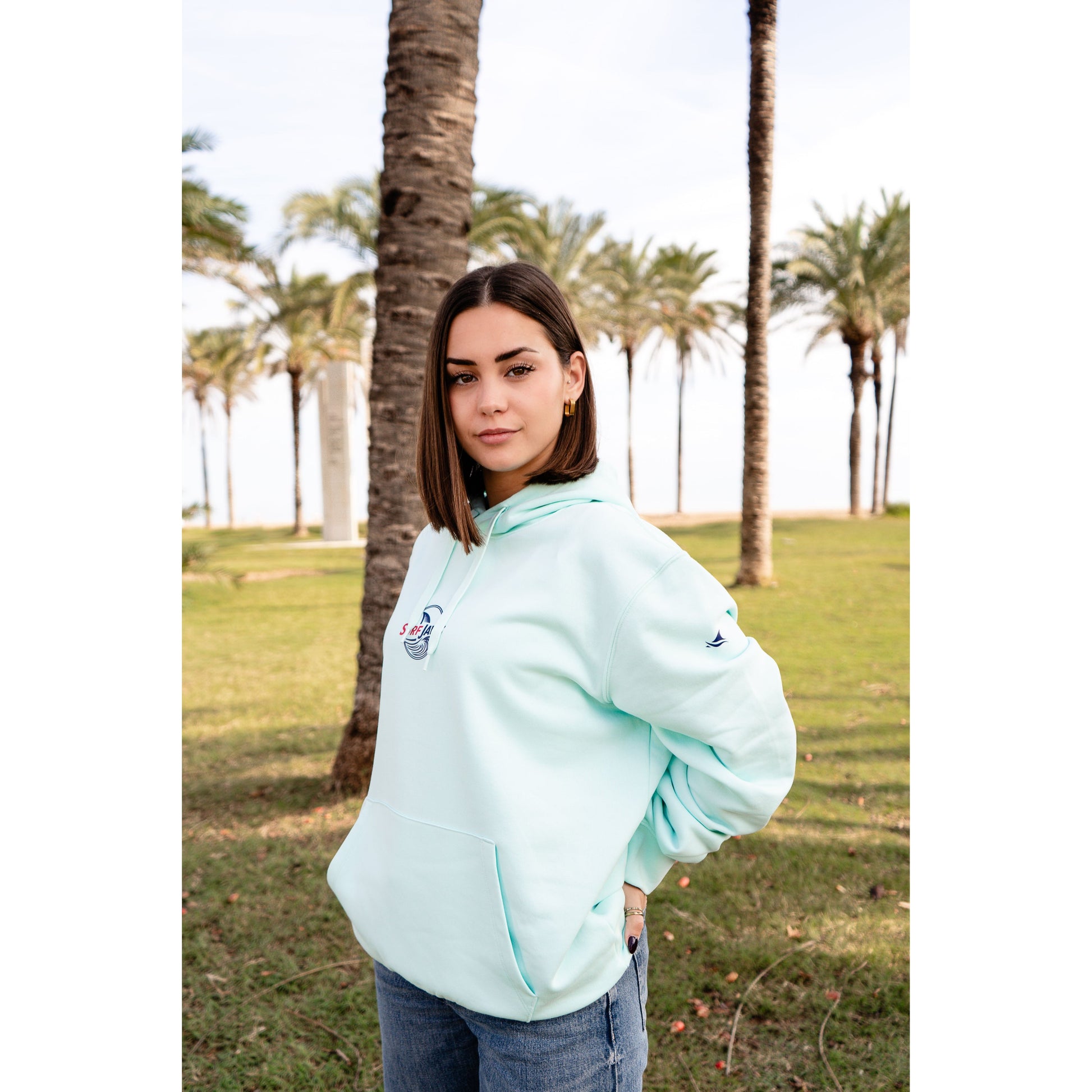 Sudadera SurfJaws de algodón orgánico en tono Ice Mint, ajuste regular. El modelo lleva una talla L, mide 1,56 m y tiene complexión normal, mostrando un estilo cómodo y ecológico