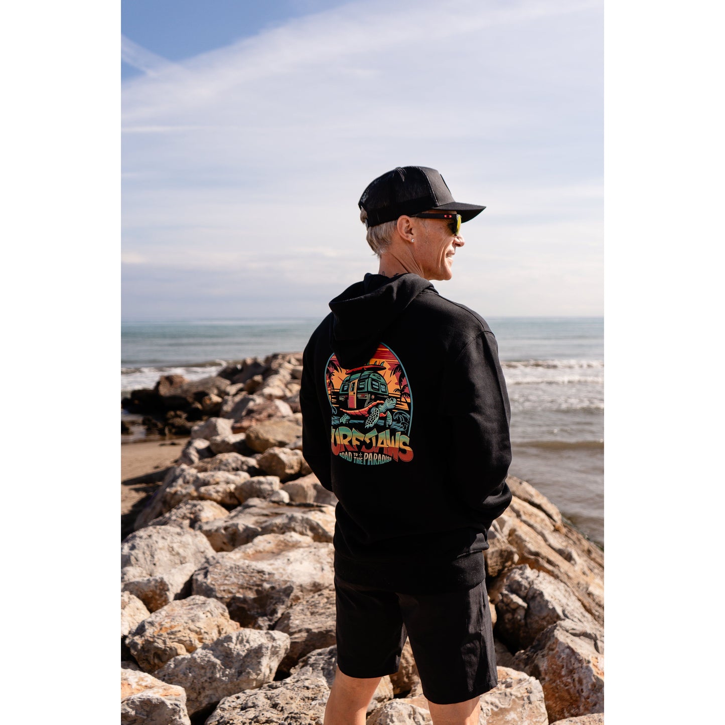 Sudadera SurfJaws de algodón orgánico en tono negro, ajuste regular. El modelo lleva una talla L, mide 1,62 m y tiene complexión atlética, mostrando un estilo cómodo y ecológico