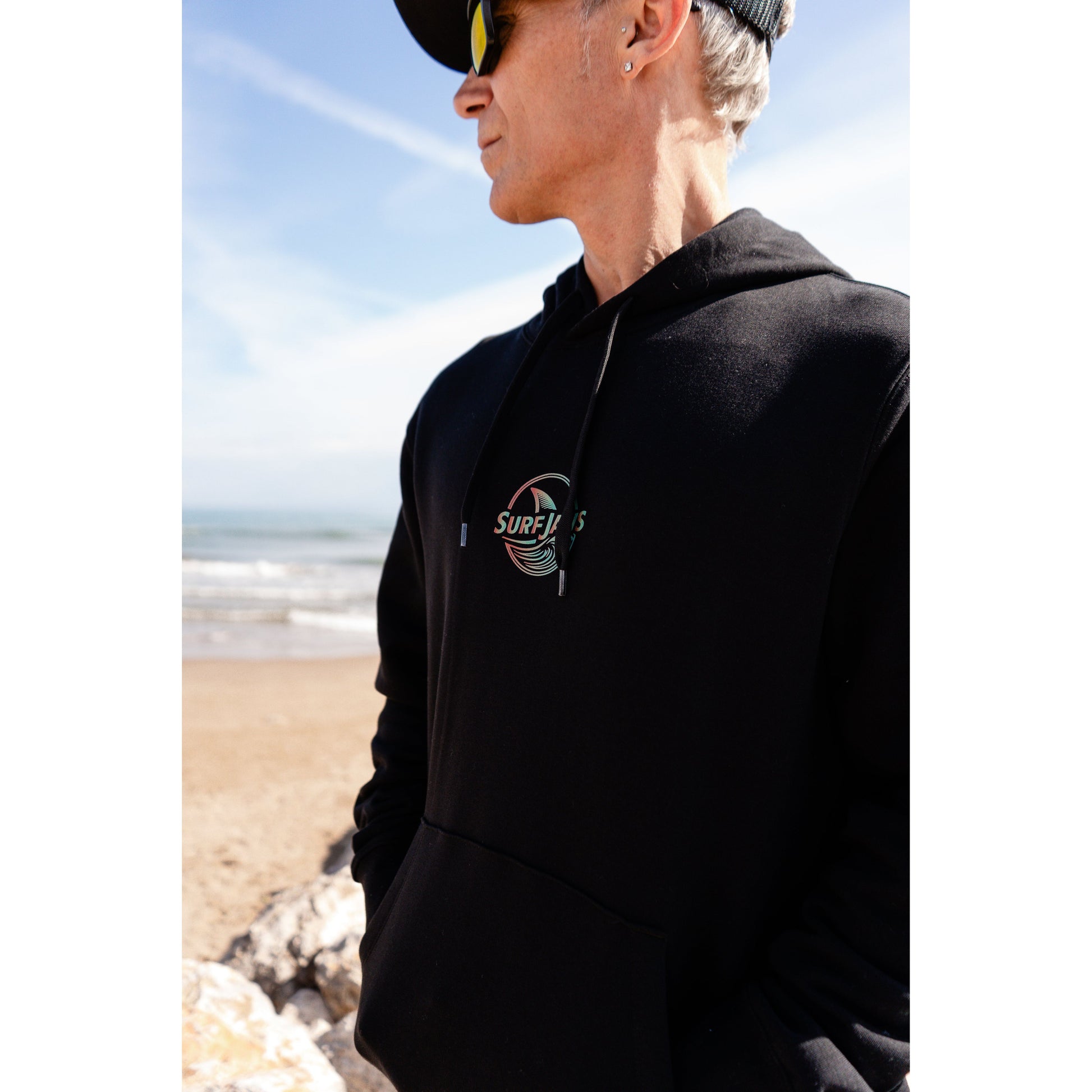 Sudadera SurfJaws de algodón orgánico en tono negro, ajuste regular. El modelo lleva una talla L, mide 1,62 m y tiene complexión atlética, mostrando un estilo cómodo y ecológico