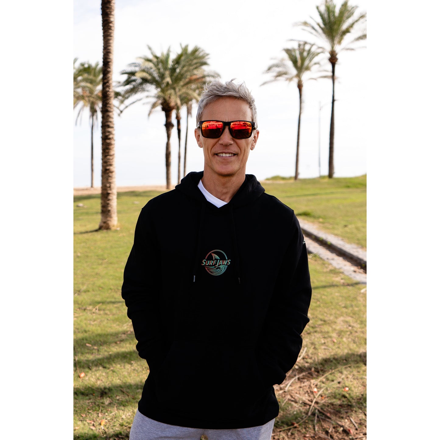 Sudadera SurfJaws de algodón orgánico en tono negro, ajuste regular. El modelo lleva una talla L, mide 1,62 m y tiene complexión atlética, mostrando un estilo cómodo y ecológico